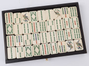 A Chinese marine ivory and bone Mah-jong set in a hardwood table cabinet with a sliding door opening to reveal five drawers with a complete set of hand painted pieces. The hardwood box has double bronze handles. Chinese character marks with the original o - 6