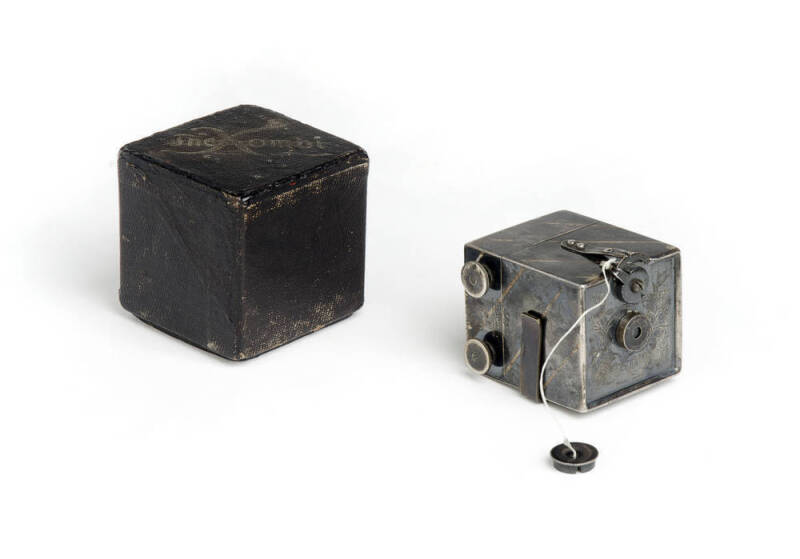 KEMPER (U.S.A.): Kombi, metal miniature box camera [#2587] with oxidized silver finish, introduced in 1892. Made to take 25 exposures on rollfilm, then double as a transparency viewer. Complete, with lens cap and original box.