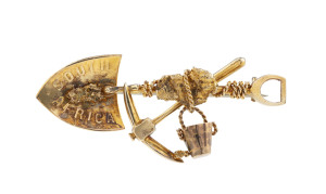 A goldminer's brooch, crossed pick and shovel with gold nugget specimens, entwined rope and bucket, stamped "South Africa, 9ct", ​4.5cm wide, 4.5 grams