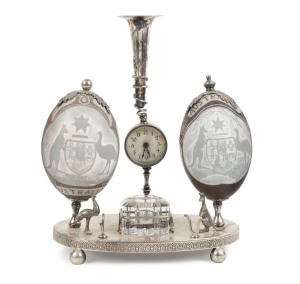 An Australiana desk set adorned with two carved emu eggs on silver plated mounts with time piece, late 19th century, 29cm high