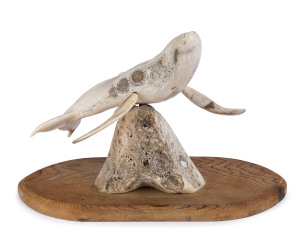 A whale ornament made from carved whalebone mounted on a hoop pine base, 19th/20th century, 20cm high, 29cm wide
