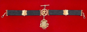 15ct gold fob (approx. 6gms) suspended from a black silk band enhanced with an additional fob featuring a 9ct gold Coat of Arms of Australia, two gold shields and gold fittings. The fob engraved verso "CORP J.C. DOGGETT 107 HOWITZER BATTERY, AUST. FIELD A