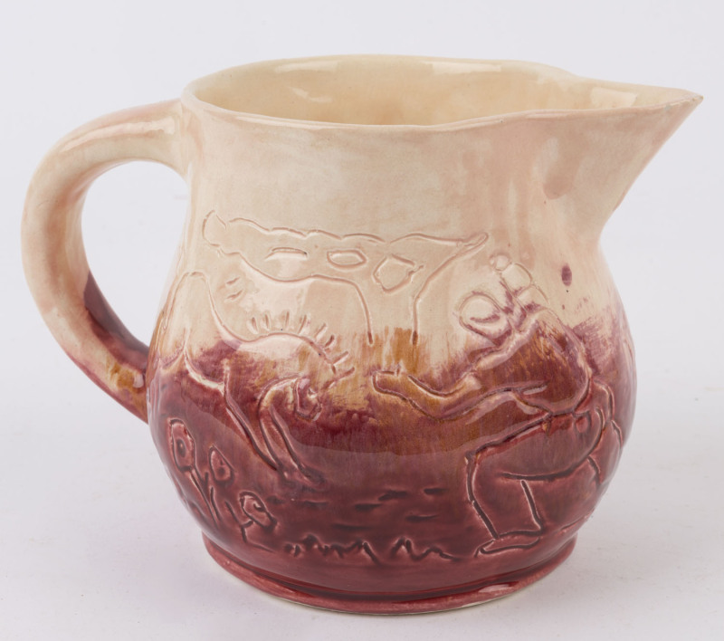 R.M.I.T. SCHOOL Melbourne, pink and burgundy glazed pottery jug with sgraffito farm scene decoration, incised signature (illegible), 14cm high, 20cm wide