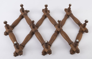 An expanding timber coat rack with porcelain studded pegs, late 19th century, 30cm high, 70cm wide