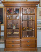 An Australian cedar bookcase, two doors with bevelled glass panels, four drawers, dentil moulded pediment and adjustable shelves, late 19th century, 211cm high, 155cm wide, 43cm deep