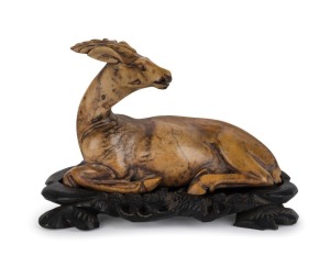 A Chinese carved stone statue of a recumbent deer on carved wooden base, 19th/20th century, 12cm high, 17cm wide overall