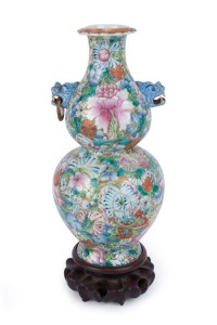 An antique Chinese double gourd shaped porcelain vase with enamel floral decoration and tiger head handles, Qing Dynasty, 18th/19th century, with carved wooden stand, iron red seal mark to base, 31.5cm high overall. PROVENANCE: Private Collection Melbourn