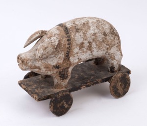 A vintage folk art pull-along pig toy, carved wood with remains of painted finish, 20th century, ​​​​​​​31cm long