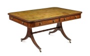 A George III English mahogany library table with embossed green leather top, attractive rounded corners with two drawers and four simulated drawer fronts to the ends and sides, supported on two double concave reeded trestles forming attractive splay legs