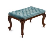 An antique English boudoir stool, carved walnut with blue velvet diamond upholstery, cabriole legs with scroll feet and original brass castors, mid 19th century, 49cm high, 80cm wide, 50cm deep