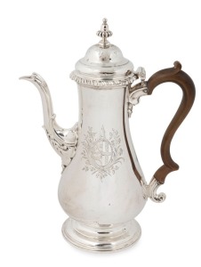 A George III English sterling silver coffee pot. A very fine example with engraved armorial crest and attractive serpentine tapering spout with an oval scalloped mount. Heavy gadrooned top rim and a circular high raised double domed cover with stylized ac