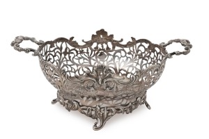 An antique English sterling silver fruit basket. Particularly well crafted in pierced silver of oval form with two shaped floral work handles and scrolling Rococo revival feet. Made by William Comyns of London, circa 1904, 15cm high, 38cm wide, 1212 grams