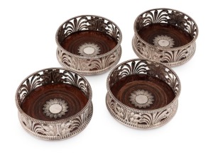 Set of four Georgian sterling silver wine decanter coasters of exceptional quality. Classical styling depicting acanthus leaves with alternate rush foliage, resting on turned mahogany bases with floral form central motifs in silver. Plain gadrooned edge t