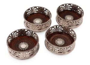 Set of four Georgian sterling silver wine decanter coasters of exceptional quality. Classical styling depicting acanthus leaves with alternate rush foliage, resting on turned mahogany bases with floral form central motifs in silver. Plain gadrooned edge to tops and bases. Maker's mark "I.B. & Co." of London, dated 1796 and 1800, 5.5cm high, 14cm diameter