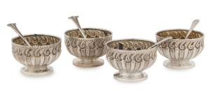 A fine quality set of four sterling silver table salts; each of circular form with repoussé decoration standing on circular feet. Accompanied by four assorted sterling silver salt spoons. Late 19th century, 150 grams total