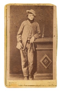 DAN KELLY photographed by Arthur BURMAN at his Burke Street East Studio, circa 1878, Albumen paper print affixed to a carte-de-visite, with "Dan Kelly" in manuscript added to the ornately printed photographer's details on the reverse; sightly cut-down (ca