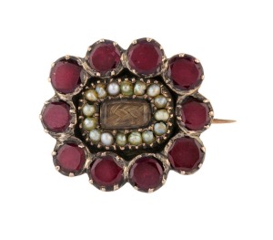 A Georgian rose gold mourning brooch set with flat cut garnets, seed pearls and woven hair centre, early 19th century, 2cm wide