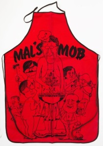 MALCOLM FRASER "MAL'S MOB" novelty apron with naked caricatures of Malcolm Fraser (wearing a "Life Wasn't Meant To Be Greasy" apron), John Howard (holding a plate), Joh Bjelke-Petersen (running with a pineapple and a banana), Andrew Peacock (sharpening a 
