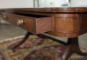A George III English mahogany library table with embossed green leather top, attractive rounded corners with two drawers and four simulated drawer fronts to the ends and sides, supported on two double concave reeded trestles forming attractive splay legs - 9