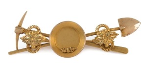 An antique gold miner's brooch with crossed pick and shovel, gold nugget specimens in gold pan, adorned with scrolling leaves on rope twists, 19th century, a fine example, ​​​​​​​6cm wide, 6.4 grams