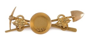An antique gold miner's brooch with crossed pick and shovel, gold nugget specimens in gold pan, adorned with scrolling leaves on rope twists, 19th century, a fine example, 6cm wide, 6.4 grams