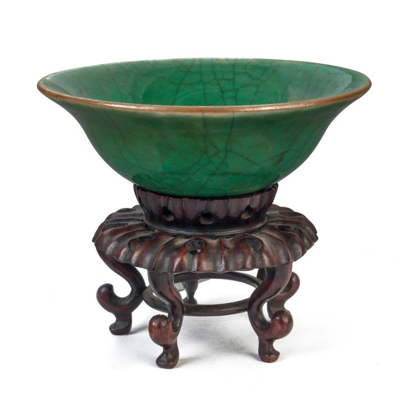 An antique Chinese celadon and jade green porcelain bowl with carved timber stand, 18th century or earlier, 7cm high, 19cm wide