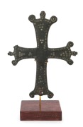 A fine Byzantine bronze crucifix. The front surface engraved with circular motif, the reverse with a dedicatory script written in old Aramaic. 10th to 12th century. 18cm high, 22cm overall