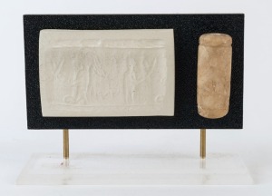 An ancient marble cylinder seal, the imprint depicting a male figure wearing a feather headdress with script in the field. Custom mounted with an impression of the seal. Hyksos Culture, Levant, circa late 2nd millennium B.C. 7cm high, 9cm high overall