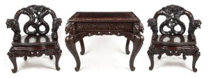 An antique Chinese table and two armchairs with carved dragon and phoenix motif, early 20th century, later ebonised finish, the table 76cm high, 100cm wide, 68cm deep