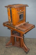 MARION & CO., large format studio camera, with mahogany body, brass fittings, rack focusing, (no lens present) on wheeled tripod base. 139cm high.