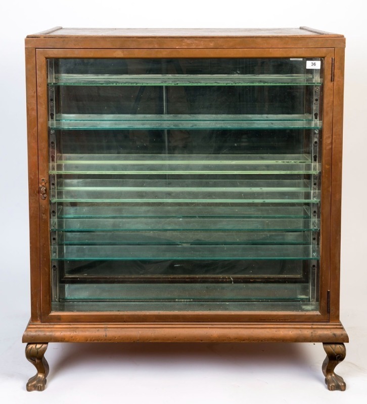 An antique shop display counter cabinet, unusual format with narrow copper front display, claw feet and shelving at the rear, circa 1900,100cm high, 87cm wide, 59cm deep