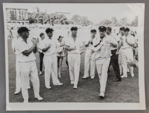 GRAHAM MCKENZIE COLLECTION - 1965-66 ASHES SERIES IN AUSTRALIA: photograph (16.5x22cm) showing McKenzie being clapped off the ground by team mates after taking 6 for 48 in England's First Innings of the 4th Test at Adelaide, signed by Graham McKenzie.