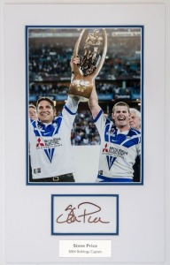 CANTERBURY-BANKSTOWN: small mounted display featuring photo Steve Price holding Premiership Cup aloft following their 2004 Grand Final win, SIGNED BY PRICE on piece beneath, overall 44x27cm, with CofA.