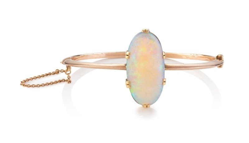 An impressive antique 9ct rose gold bangle set with a superb solid opal approximately 15-20ct, (3 x 1cm), late 19th century, stamped "9C", the bangle 6.5cm wide, 14.7 grams total