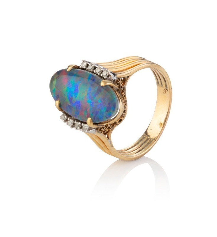 A yellow gold ring set with an oval opal doublet flanked by four white brilliant cut diamonds on each shoulder, circa 1970, 4.6 grams total