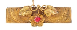 A Colonial Australian 15ct yellow gold brooch with engraved decoration adorned with applied leaves set with red stone, 19th century, 4.5cm wide, 5 grams
