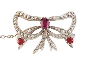 A vintage 9ct white gold bow brooch set with three cut garnets, early to mid 20th century, 3.5cm wide, 11.2 grams Accompanied by a Pilkington Jewellers valuation of $1000