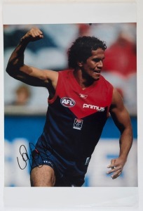 MELBOURNE - PLAYER SIGNED COLOUR PRINTS: action images (46x31) of Aaron Davey, Cameron Bruce and Jack Watts; also a copy of artwork by Paul Harvey showing Ron Barassi, boldly signed by the Demons legend. (4 items)