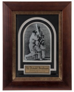 DON BRADMAN signed photograph, attractively framed together with a plaque describing his Test match statistics; overall 46 x 36cm.Bradman is captured in his follow-through, watching the ball he has hit to the boundary, with the keeper, Godfrey Evans, frozen in time with his empty gloves in the catching position.