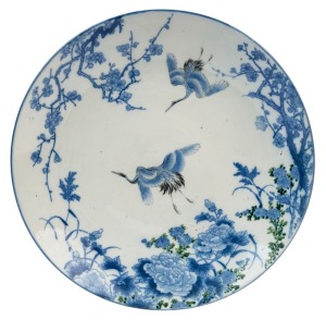 A Japanese porcelain charger with two cranes in flight and blossom decoration, late Edo / early Meiji Period, mid 18th century, 42cm diameter