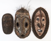 Three tribal masks, carved wood, shell, cane and feather with ochre decoration, Papua New Guinea, the largest 55cm high