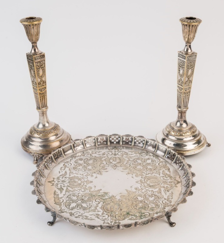 An antique English silver plated serving tray, and a pair of antique German silver plated candlesticks, 19th century, (3 items), the tray31cm diameter, the candlesticks 29cm high