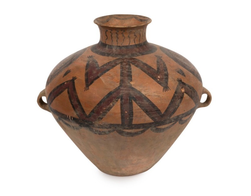  A Chinese lugged Neolithic painted clay vessel with geometric designs within spheres and large stylized figures extend upwards towards the flared spout. Neolithic Culture, circa 3rd to 2nd millennium B.C. 37cm high