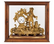 An antique French mantel clock in figural gilt metal case with time and strike movement, enamel dial and Roman numerals, 19th century, with original carved and gilded stand, and housed in a later timber and glass case, (3 items),  the clock is 35cm high 4