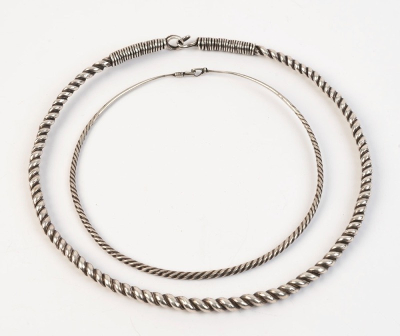 Two tribal silver neck rings, Southeast Asian origin, early to mid 20th century, ​​​​​​​the larger 20th wide