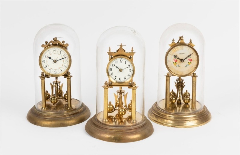 Three German 400 day anniversary clocks in glass and perspex domes, 20th century, ​​​​​​​the largest 29cm high