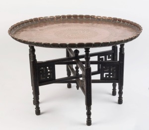 A Middle Eastern folding table with ornate circular copper top, 19th/20th century, ​​​​​​​48cm high, 74cm diameter