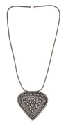 An antique Malay silver modesty disc (caping) of heart shape. The main decorative border is embedded with a row of padi seeds followed by a row of embossed dots inside a thin border. The central shield adorned with floral decoration. With original silver 