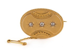 An Aesthetic Movement 18ct yellow gold oval brooch set with three diamonds, housed in a plush fitted box, circa 1870s. Reverse with locket window back. 4cm wide, 14 grams total