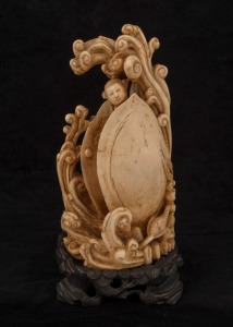 A Chinese carved ivory statue of a female standing nude in waves and clam shell, on wooden stand, early to mid 20th century, 22cm high overall